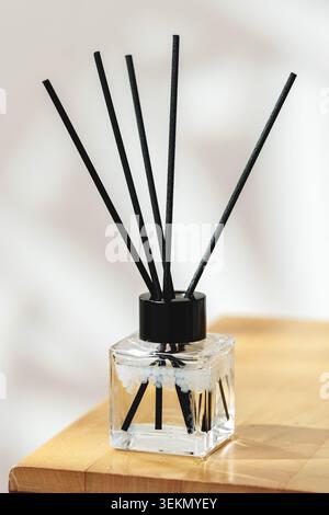 Duftdiffusor mit schwarzen Stäben auf Holztisch in sanftem Licht Stockfoto