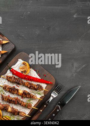 Gegrillte Fleischspieße, serviert mit Gemüse auf Holzbrettern in einer Küche Stockfoto