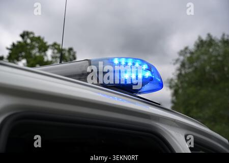 Blinkender blauer Lichtbalken an einem deutschen Polizeiauto vor dunklem bewölktem Himmel, Warnsignal während einer Operation zum Schutz der Öffentlichkeit, Kopierraum, auswählen Stockfoto
