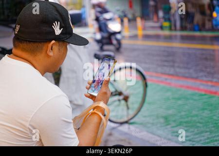 Yilan, Taiwan - 31. März 2025: Ein einwandernder Fischer ruft sein Kind auf einer Straße in Nanfangao an, was die Sehnsucht ausländischer Arbeiter widerspiegelt Stockfoto