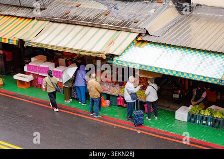 Yilan, Taiwan - 31. März 2025: Die Einwohner stöbern bei regnerischem Wetter unter farbenfrohen Markisen auf dem Nanfangao Morning Market. Stockfoto