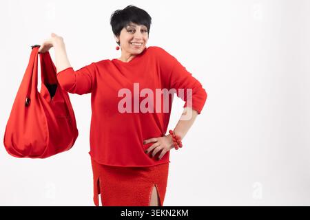 Fröhliche Erwachsene Frau, die große rote, stilvolle Handtasche hält und lächelt Stockfoto