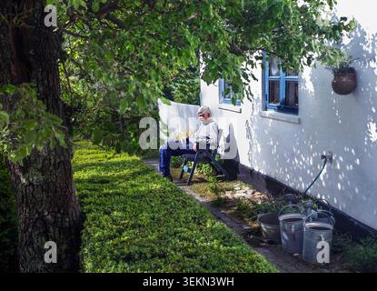 Senior Mann, der Freizeit auf einem Stuhl im Garten verbringt Stockfoto