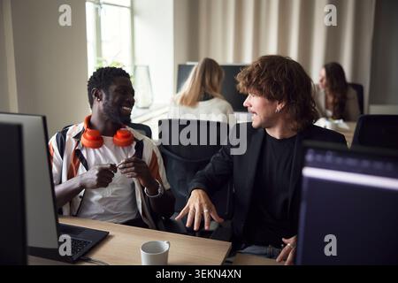 Hochwinkelansicht männlicher Geschäftsexperten, die miteinander sprechen, während sie am Schreibtisch sitzen Stockfoto