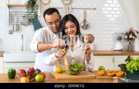 Junge asiatische Familie Paare haben Spaß Kochen und bereiten kochen vegane Lebensmittel gesund essen mit frischem Gemüsesalat auf der Theke in der Küche zu Hause.Happy Stockfoto