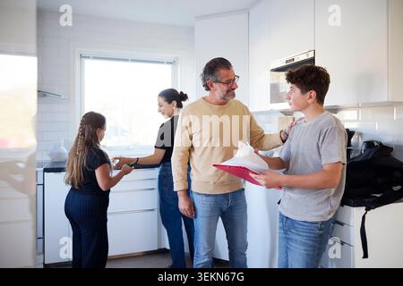 Ein lächelnder Mann gratuliert seinem Sohn zum bestandenen Examen zu Hause Stockfoto