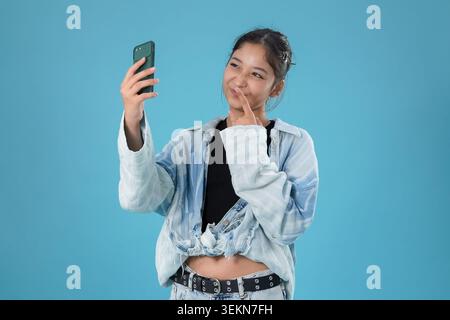 Authentisches emotionales Porträt, das eine fröhliche junge asiatische Frau zeigt, die sich selbst nimmt Stockfoto