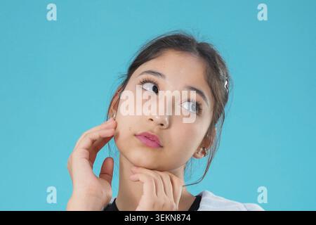 Authentisches emotionales Porträt, das nachdenkliche junge asiatische Frau zeigt, die die Wange berührt Stockfoto