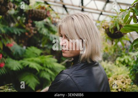Lächelnde Frau mit blondem Haar, die über die Schulter schaut Stockfoto