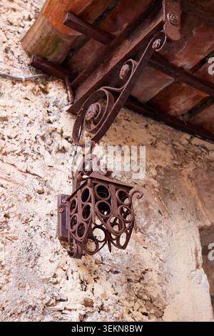 Alte, schmiedeeiserne Laterne hängt an einer alten rustikalen Steinmauer. Stockfoto