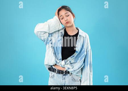 Authentisches emotionales Porträt, das müde junge asiatische Frau zeigt, die den Hals fe berührt Stockfoto
