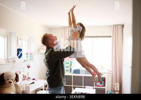 Vater spielt mit Tochter im Schlafzimmer zu Hause Stockfoto