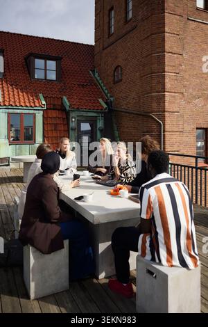 Gruppe von verschiedenen Geschäftsleuten diskutieren, während sie am Tisch auf der Büroterrasse sitzen Stockfoto