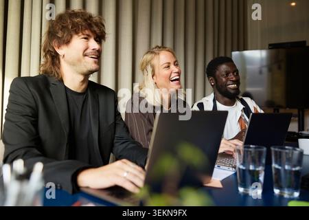 Glückliche Unternehmerinnen und Unternehmerinnen lachen bei Geschäftstreffen Stockfoto