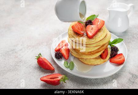 Stapel Pfannkuchen mit Erdbeeren, Brombeeren und Minze, mit Sirup übergossen Stockfoto