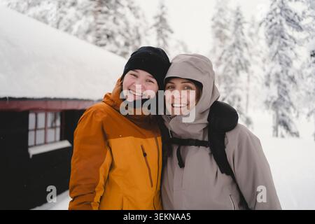 Porträt einer glücklichen Frau, die mit ihrer Tochter im Winterwald posiert Stockfoto