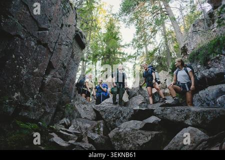 Gruppe von Freunden, die auf Felsen stehen, während sie im Wald wandern Stockfoto