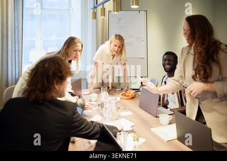 Gruppe von verschiedenen Unternehmern, die Strategien diskutieren, während sie im Büro um einen beleuchteten Tisch stehen Stockfoto
