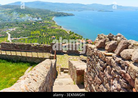 Die Aussicht von den alten Steinruinen auf der Burg Molyvos zeigt die üppige grüne Landschaft, die charmanten Dächer des griechischen Dorfes und die glitzernden blauen Stockfoto