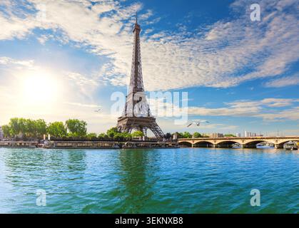 Ein atemberaubender Panoramablick auf den berühmten Eiffelturm, der majestätisch neben einer Steinbrücke über das ruhige Wasser der seine steht. Die Stadt Stockfoto