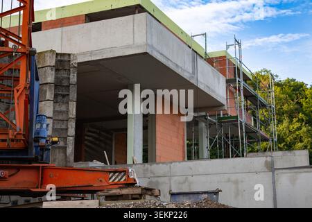 Dieses professionelle Foto für den Außenbereich zeigt eine moderne Baustelle mit schweren Maschinen und neuen Bauelementen, die sich in der Entwicklung befinden. Auf der linken Seite die untere Metallstruktur eines großen Stockfoto