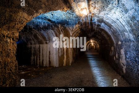 Der historische Bunkertunnel aus dem 2. Weltkrieg, der mit Stahlbeton gebaut wurde, ist heute ein unheimlicher verlorener Ort im Dunkeln mit Stalaktiten, alten Glühbirnen und feuchten Wannen Stockfoto