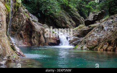 Wasserfall des Flusses Sanzhanxi in Taroko. Kristallklares türkisfarbenes Wasser fließt durch einen felsigen Canyon. Üppig grüner Wald umgibt den Gebirgsbach. Stockfoto