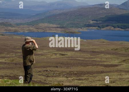 Mann mittleren Alters, der am Fuße des Meall Liath na Doire in Richtung Loch Eigheach und Rannoch Station steht Stockfoto