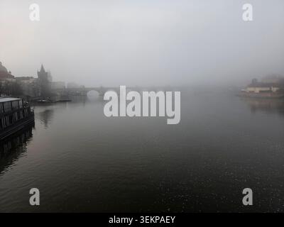 Ätherischer, atmosphärischer Blick auf eine alte Steinbogenbrücke über einen Fluss, der von dichtem Nebelnebel umhüllt ist, unterstreicht die architektonische Schönheit Stockfoto