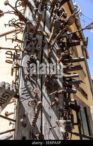 Eine detaillierte vertikale Aufnahme eines traditionellen mittelalterlichen Gildenpfahlmonuments, bedeckt mit zahlreichen antiken Eisennägeln, Pfeilspitzen und kundenspezifischen Metallplatten Stockfoto