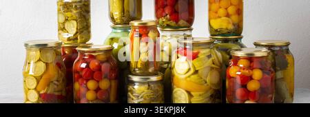 Canning ist eine häufige Aktivität in der Küche, da die Theke mit Gemüse und Obst gefüllte Gläser säumen. Diese Praxis hilft dabei, Lebensmittel für den Gewinn zu bewahren Stockfoto