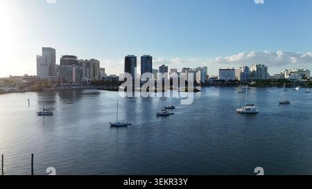 Blick aus der Vogelperspektive auf die Skyline von Palm Beach mit modernen Wolkenkratzern und Segelbooten, die auf dem ruhigen blauen Wasser unter klarem Himmel in Palm Beach, Florida, ankern. Stockfoto