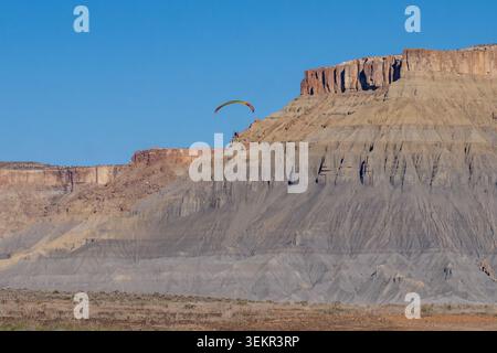 Ein Paramotor-Pilot, der an der North Caineville Mesa in der Caineville Desert, Utah, vorbeifliegt. Stockfoto