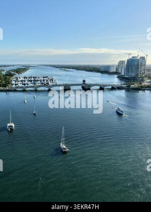 Blick aus der Vogelperspektive auf den Intracoastal Waterway mit Segelbooten in der Nähe einer Brücke und der Skyline der Stadt in Palm Beach, Florida, USA. Stockfoto