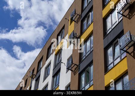 Ein modernes Gebäude mit mehreren Fenstern und Klimaanlage an der Fassade. Die Szene findet an einem sonnigen Tag mit Wolken statt Stockfoto