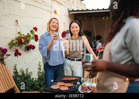 Verschiedene glückliche Frauen reden und lachen beim Grillen im Freien Stockfoto