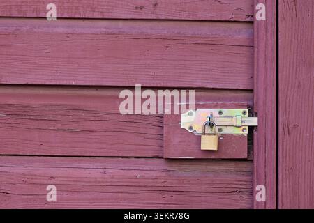 Messing-Vorhängeschloss an einer hölzernen Schiebetürverriegelung Stockfoto