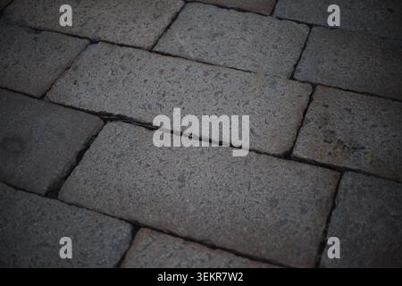 Eine detaillierte Nahansicht eines alten Kopfsteinpflasters mit verwitterten grauen Steinblöcken in klassischem Muster. Stockfoto
