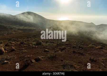 Niedrige Wolken, die bei Sonnenaufgang über eine vulkanische Berglandschaft im Teno Rural Park, Teneriffa, Kanarischen Inseln, Spanien treiben. Stockfoto