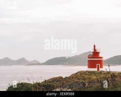 Der berühmte leuchtend rote Punta Robaleira Leuchtturm auf den zerklüfteten Felswänden von Costa da Vela, Cangas, Galicien, Spanien. Atlantik Stockfoto
