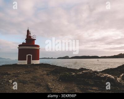 Der berühmte leuchtend rote Punta Robaleira Leuchtturm auf den zerklüfteten Felswänden von Costa da Vela, Cangas, Galicien, Spanien. Atlantik Stockfoto