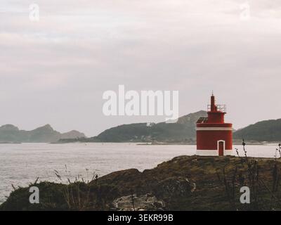 Der berühmte leuchtend rote Punta Robaleira Leuchtturm auf den zerklüfteten Felswänden von Costa da Vela, Cangas, Galicien, Spanien. Atlantik Stockfoto