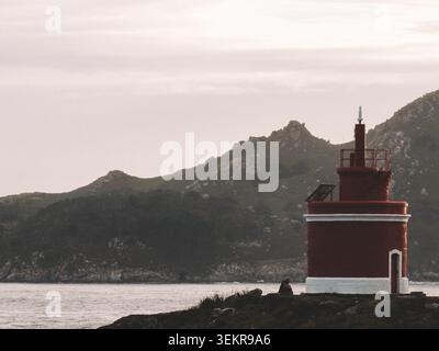 Der berühmte leuchtend rote Punta Robaleira Leuchtturm auf den zerklüfteten Felswänden von Costa da Vela, Cangas, Galicien, Spanien. Atlantik Stockfoto