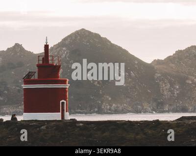 Der berühmte leuchtend rote Punta Robaleira Leuchtturm auf den zerklüfteten Felswänden von Costa da Vela, Cangas, Galicien, Spanien. Atlantik Stockfoto