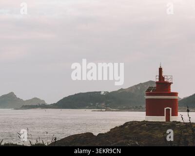 Der berühmte leuchtend rote Punta Robaleira Leuchtturm auf den zerklüfteten Felswänden von Costa da Vela, Cangas, Galicien, Spanien. Atlantik Stockfoto