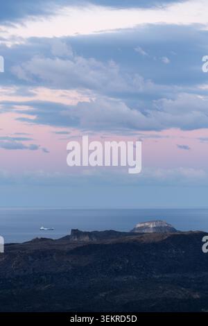 Blick auf das Meer und die Felsformationen unter bewölktem Himmel in der Abenddämmerung in Santorin, Griechenland Stockfoto