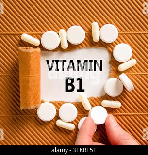 Vitamin B1-Symbol. Konzeptworte Vitamin B1 auf wunderschönem Weißbuch. Weiße Tabletten. Die Hand des Arztes. Schöner brauner Hintergrund. Medizinisch gesund Stockfoto