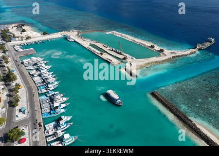 Aus der Vogelperspektive auf einen geschäftigen Hafen mit angedockten Booten und Bauarbeiten an einer Mole in Kudahuvadhoo, Dhaalu Atoll, Malediven. Stockfoto