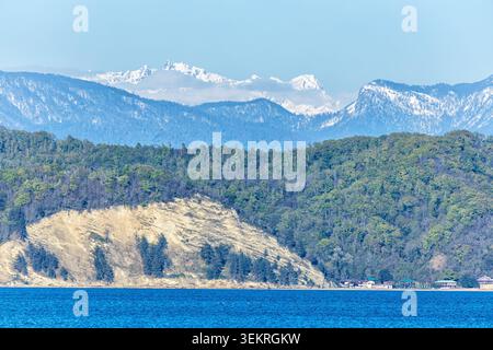 Die Küste mit hohen schneebedeckten Berggipfeln im Hintergrund Stockfoto