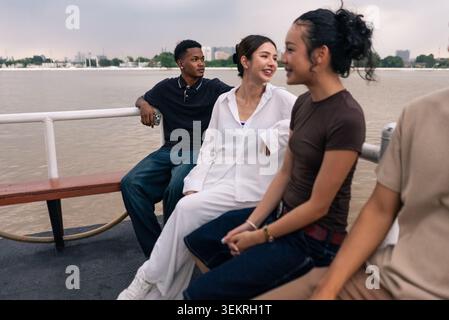 Junge, vielfältige Freunde, die eine entspannende Bootsfahrt auf dem städtischen Fluss genießen Stockfoto